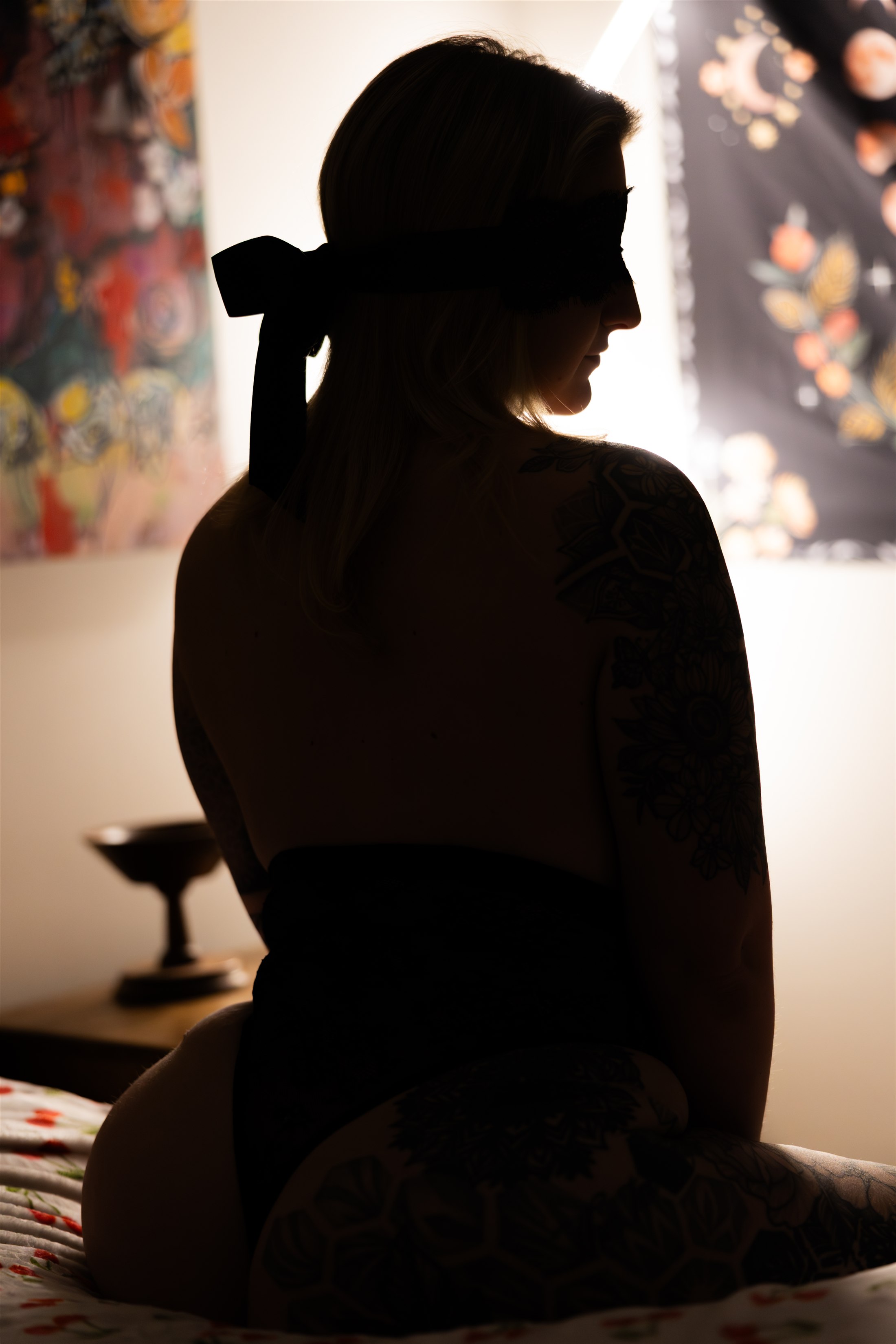Veronica in silhouette, wearing a black lace mask and looking over her shoulder